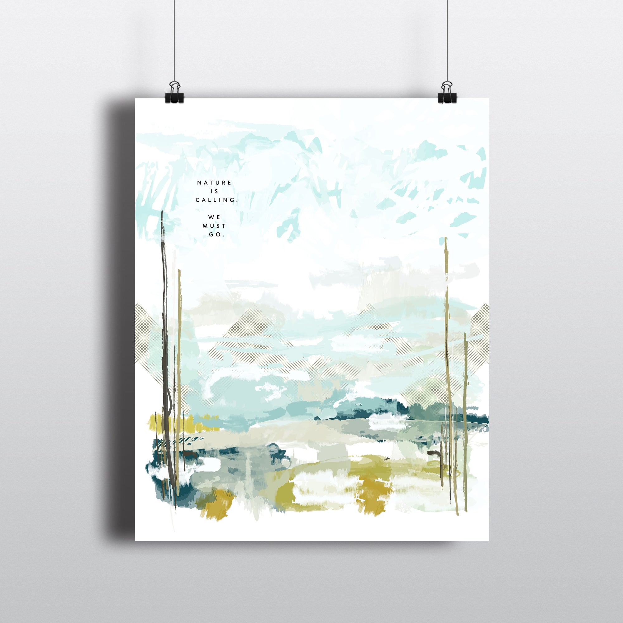 ART PRINT FEATURING NATURE SCENE WITH MOUNTAINS AND THE TEXT NATURE IS CALLIING, WE MUST GO. SHOWN HANGING WITH CLIPS
