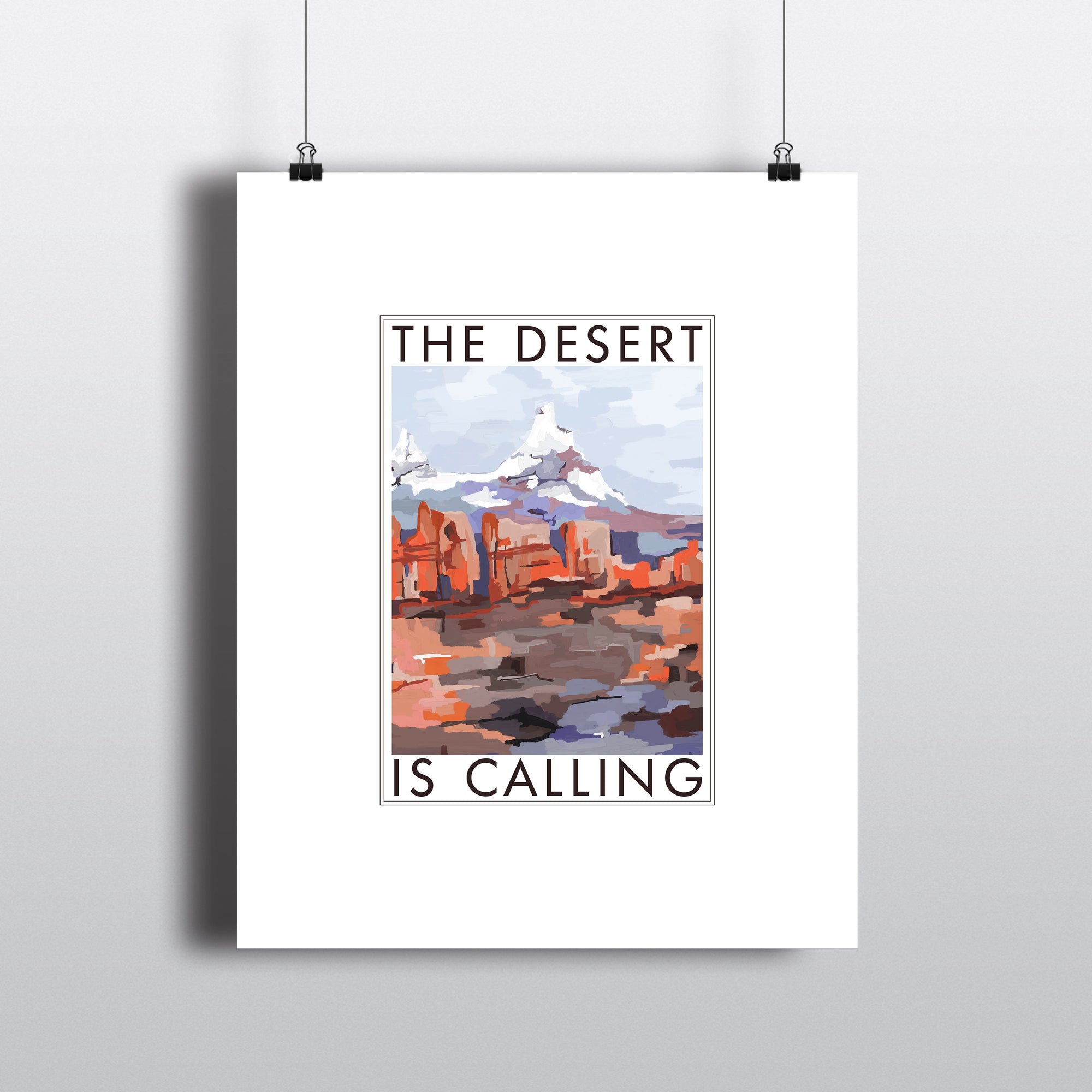 Art print with white border, THE DESERT IS CALLING text  framing abstract art of desert and mountain. Hanging by clips. 